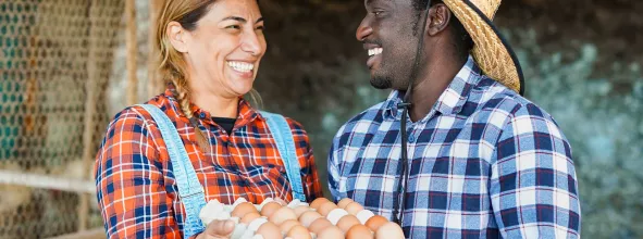 Two farmers smiling while holding a tray of eggs