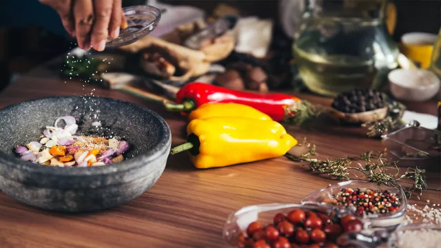 Ingredients on a wood table, handing pouring salt into a mortar