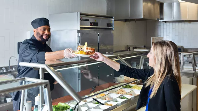 Cook passing sandwich to customer