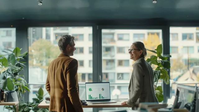 Two people overlooking report on laptop in office