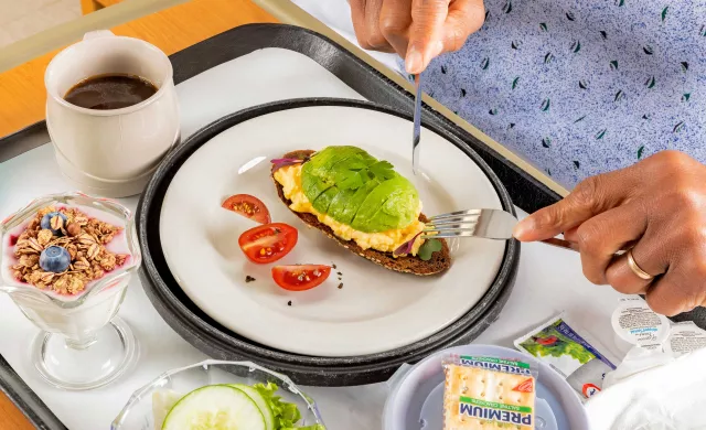 Overhead shot of hospital tray with avocado toast, coffee and yogurt