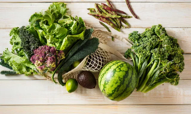 Reusable grocery bag with vegetables on wood table