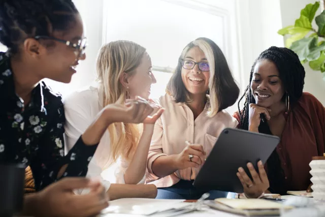 Diverse group of individuals working around a tablet