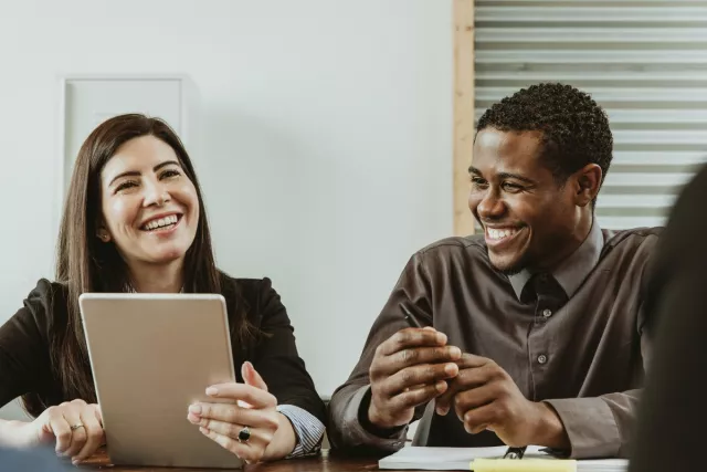 Co-workers overlooking at a tablet while smiling