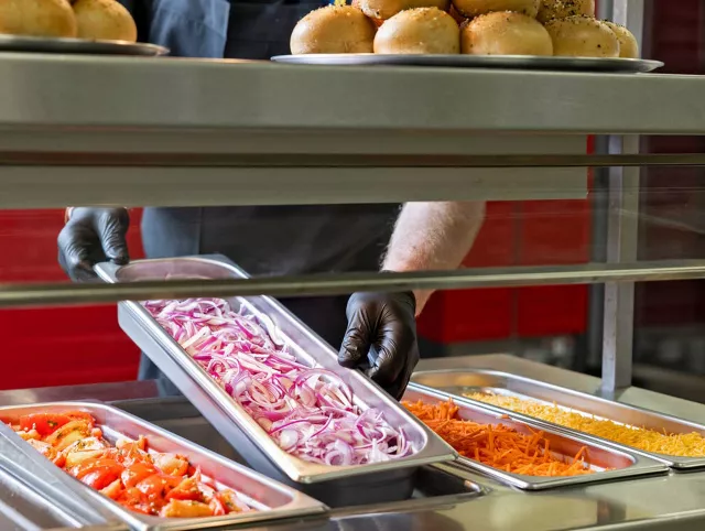 Cook playing pan of red onions onto salad line